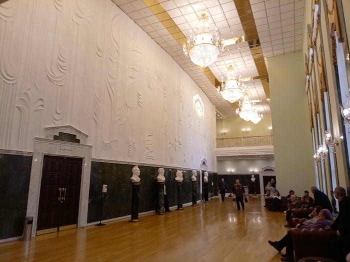 Другая сторона выводит в фойе с кожаными диванами, столиками и бюстами известных композиторов, и задними дверями партера.