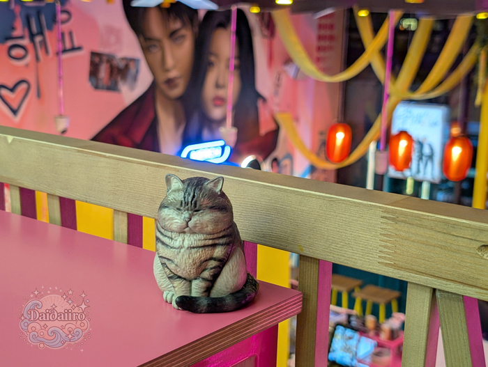 Он на фоне стенда с айдолами. Кто из них главный на этом фото — решать вам.