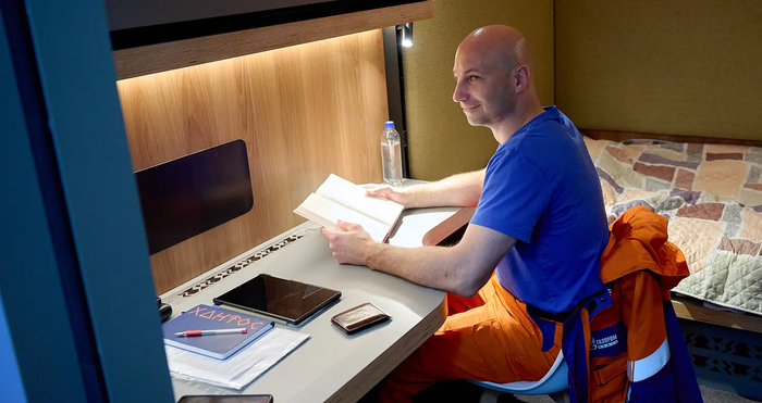 Вахтовик читает книгу в своем жилом модуле на месторождении Александра Жагрина