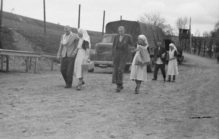 Французские медсестры ведут истощенных узников концлагеря Файинген к машинам.