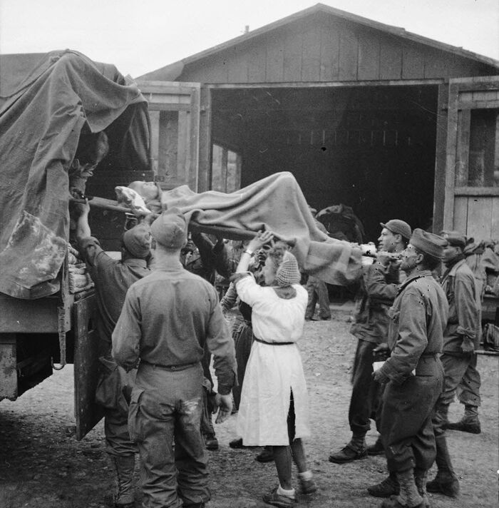 Французские медсестры и солдаты грузят носилки с истощенными узниками концлагеря Файинген.