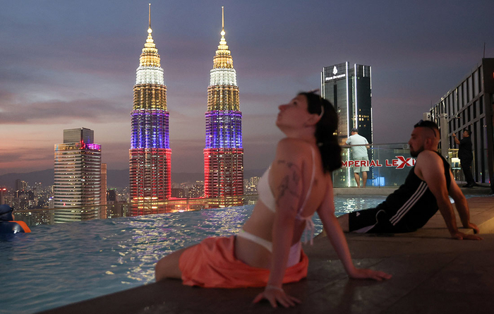 Люди у бассейна с видом на башни Петронас в Куала-Лумпуре//Фото: Валерий Шарифулин/ТАСС