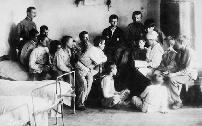 Чтение в спальне колонистов. Слева стоит А. С. Макаренко. 1921